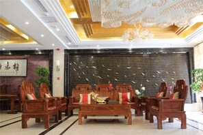 Un vestíbulo con muebles de madera, una pared negra con líneas verticales y un candelabro.