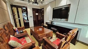 A living room with a wooden sofa set, a coffee table, and a flat-screen TV mounted on the wall. - Fengda Vista Hotel (Wuwei No.2 Middle School Pedestrian Street) (Wuwei)