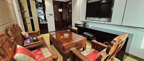 A living room with a wooden sofa set, a coffee table, and a flat-screen TV mounted on the wall.