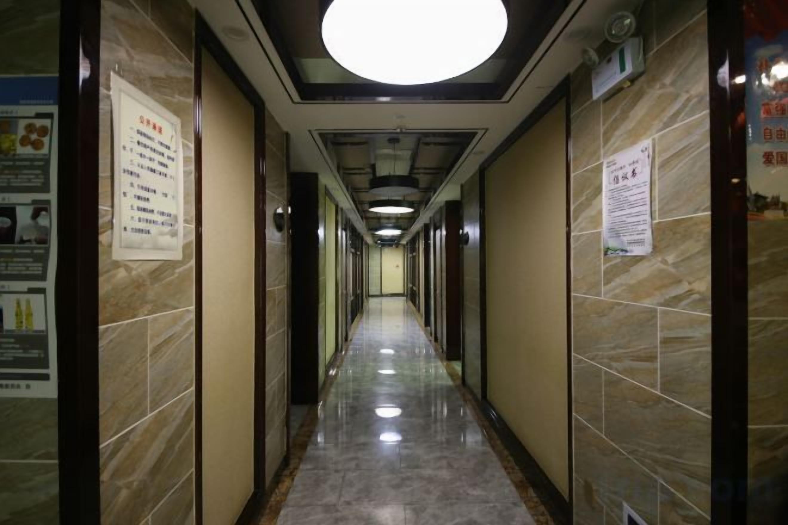 A hallway with marble walls, a tiled floor, and a ceiling light.