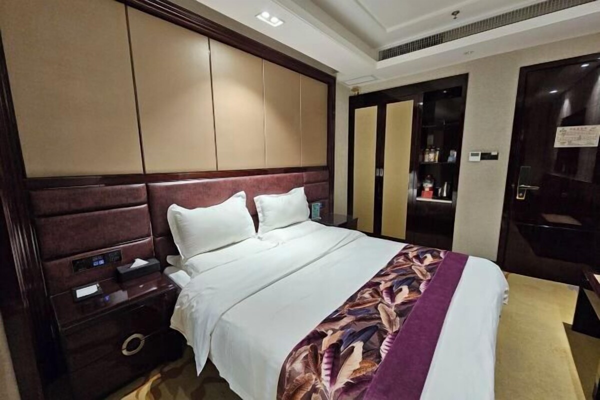 Une chambre d’hôtel avec un grand lit, une table de chevet, une armoire et une porte dotée d’un miroir.
