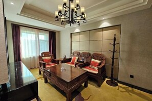 A traditional-style room with a large wooden table, two upholstered chairs with red cushions, a decorative coat stand, and a large window with curtains. - Fengda Vista Hotel (Wuwei No.2 Middle School Pedestrian Street) (Wuwei)