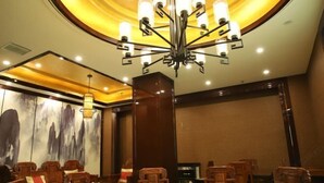 A conference room with a round table, wooden chairs, a chandelier, and a large abstract painting on the wall. - Fengda Vista Hotel (Wuwei No.2 Middle School Pedestrian Street) (Wuwei)