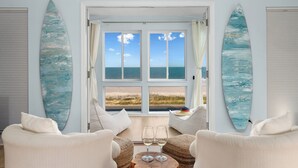 Una stanza con vista sulla spiaggia, due tavole da surf, un tavolo con bicchieri e due sedie.