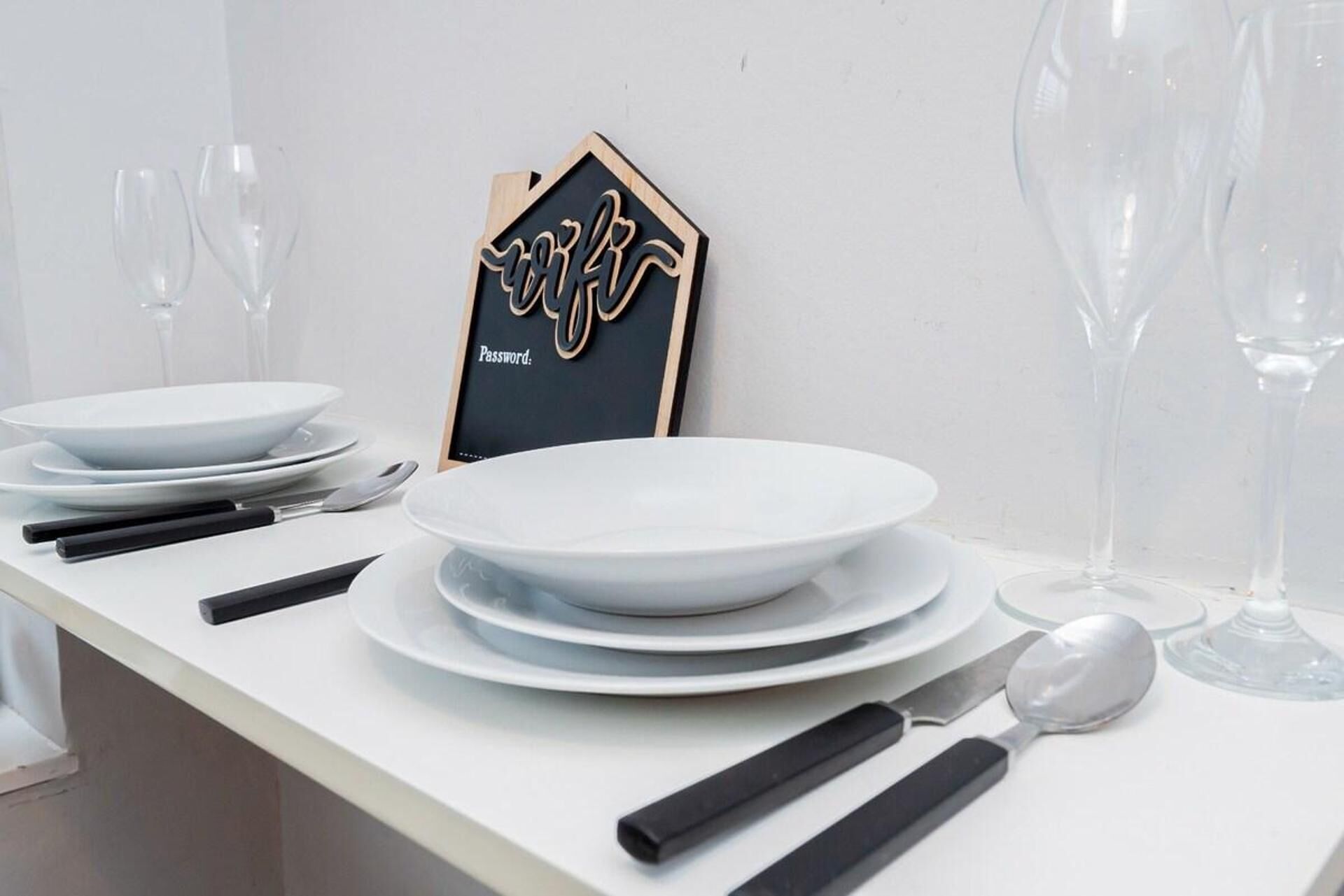 A table set with white plates, black-handled cutlery, and a blackboard with a decorative design and the word "Password".