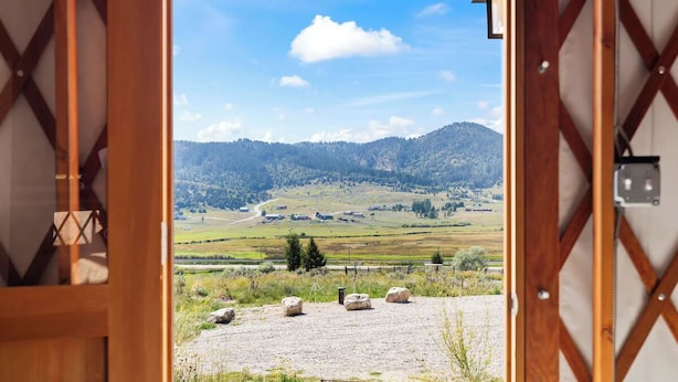 A wooden deck with a view of a rural landscape, including fields and distant mountains.