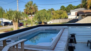 Un bain à remous rectangulaire, doté d’un escalier en bois et entouré d’une terrasse en bois.