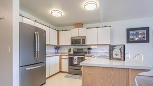 A modern kitchen with a stainless steel refrigerator, microwave, oven, and a wooden island.