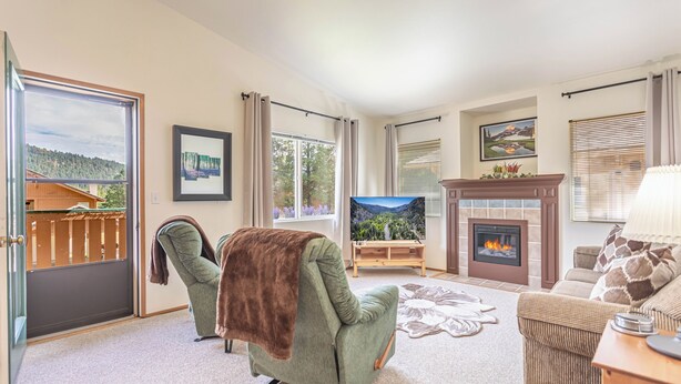 A living room with a fireplace, a sofa, a chair, and a TV.