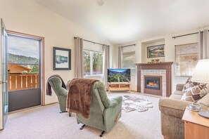 Ein Wohnzimmer mit Kamin, einer Couch, einem Sessel und einem Fernseher.