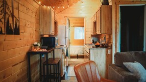 Un accogliente interno di una baita con pareti in legno, angolo cottura, sala da pranzo e soggiorno.