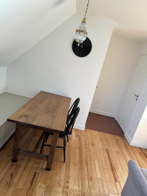Een eetruimte met een houten tafel en stoelen, een kroonluchter en een visgraatvloer.