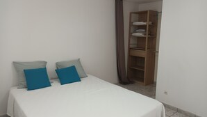 Une chambre à coucher avec un lit, deux oreillers et une armoire en bois.