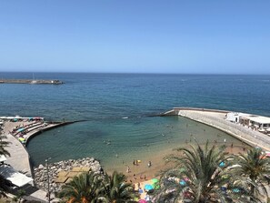 Une plage côtière offrant une vue dégagée sur la mer, un rivage rocheux et une jetée en arrière-plan.