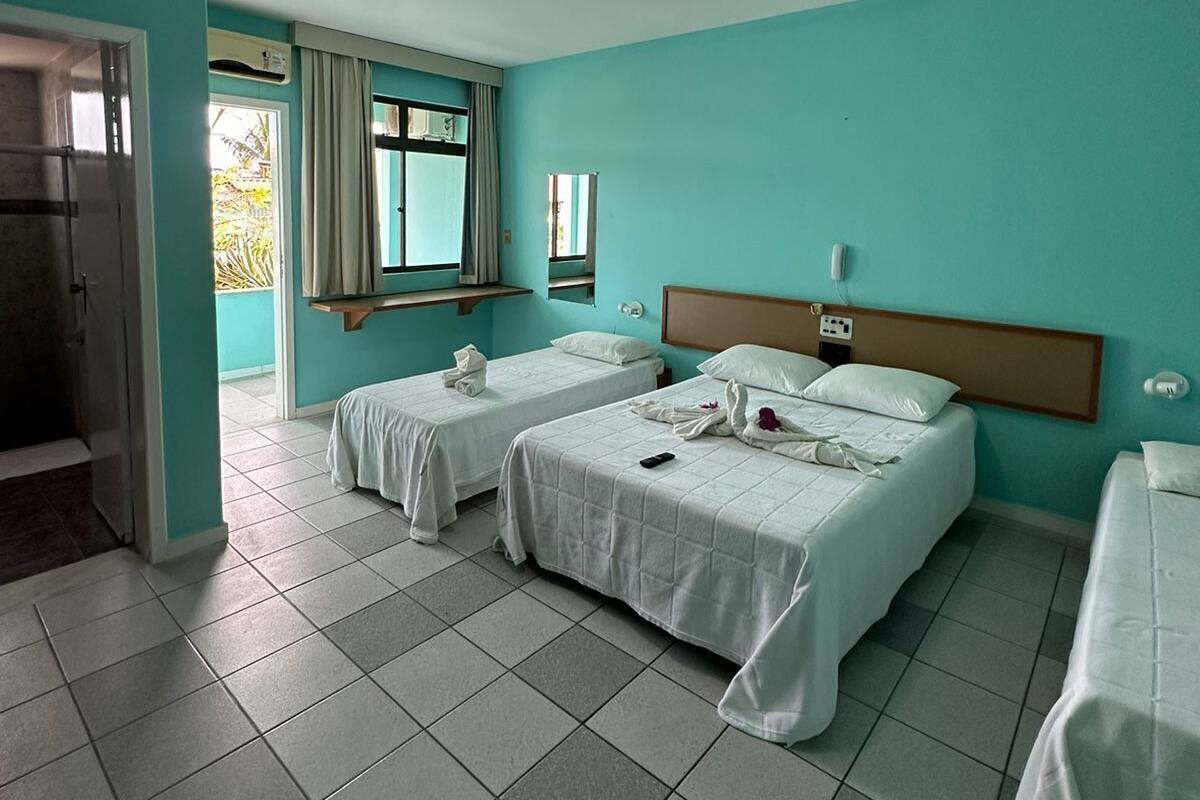 Habitación de hotel con dos camas, una ventana con cortinas, un espejo y una lámpara en el techo.