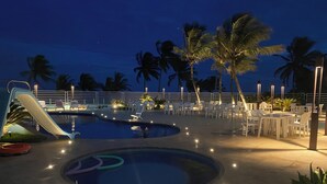 A pool area with a slide, lounge chairs, and palm trees. - Hotel Paraiso Tropical (Alcobaca)