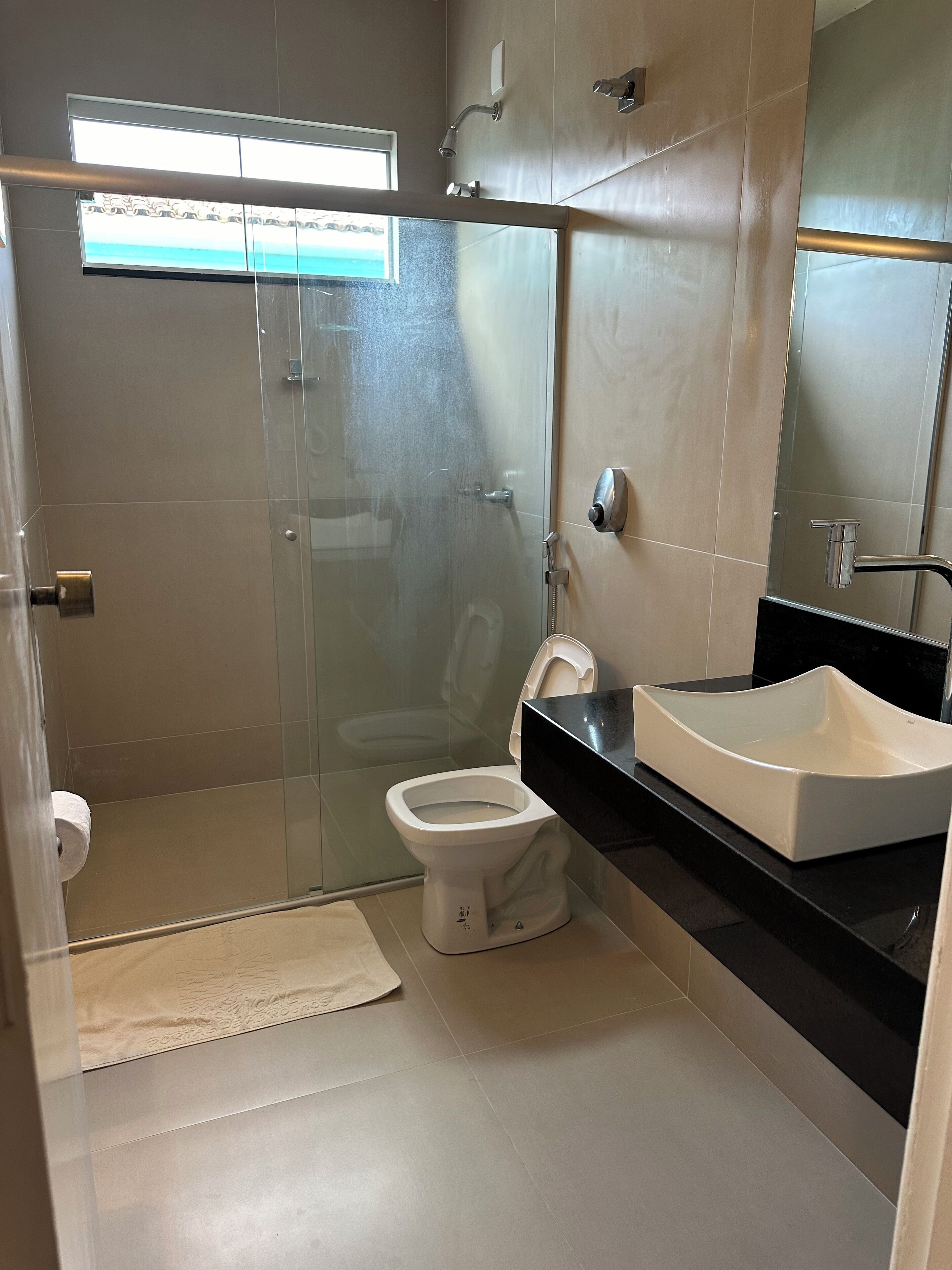 A modern bathroom with a glass-enclosed shower, a white toilet, and a black countertop with a white sink.