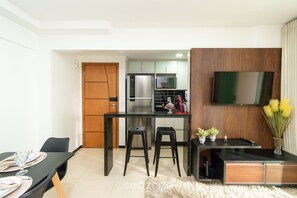 Een moderne keuken met een koelkast, magnetron en een eethoek met een tafel en stoelen.