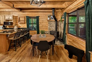 A cozy cabin interior with a dining area, kitchen, and a fireplace.