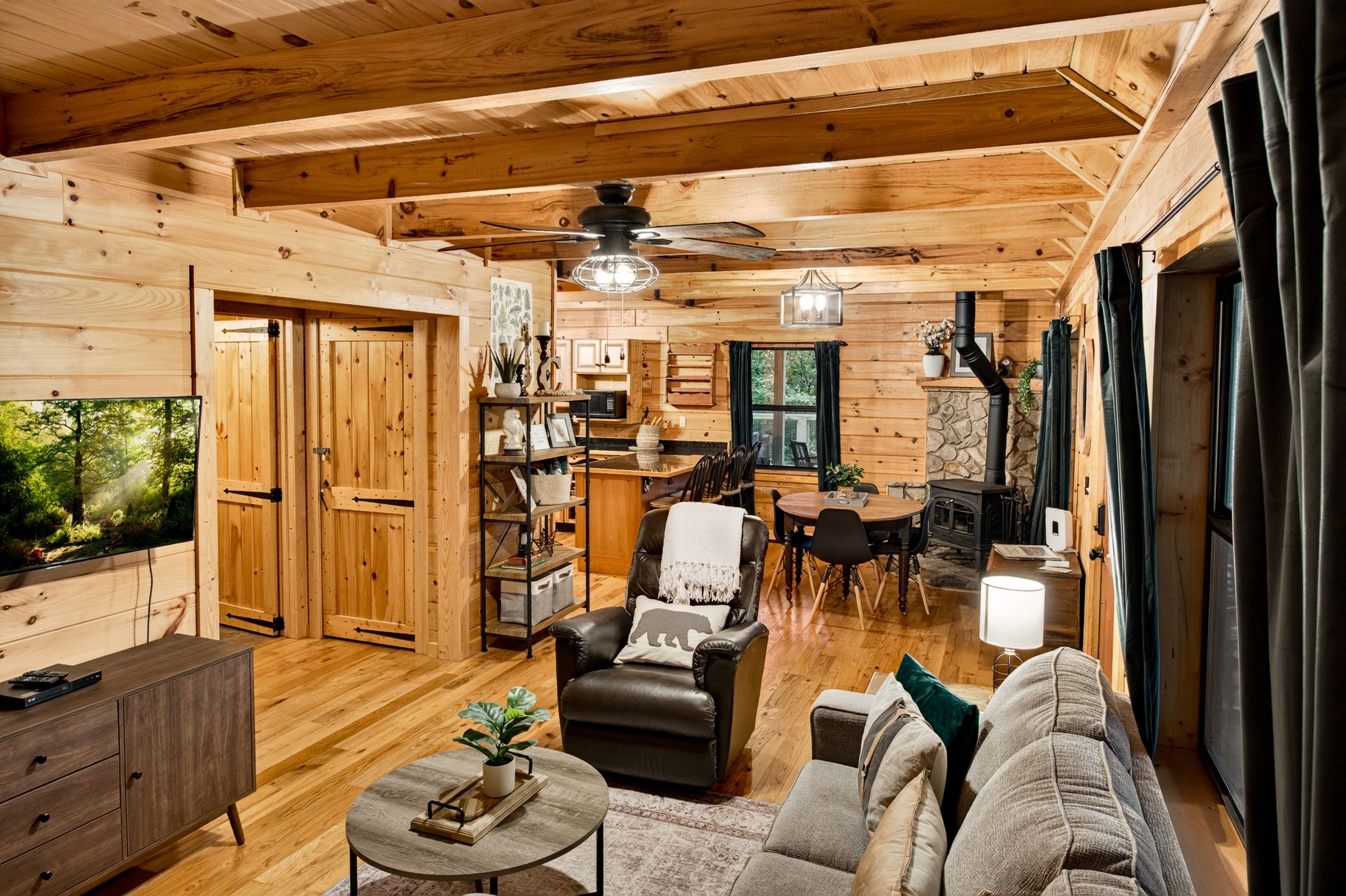 Interior acogedor de una cabaña con comedor, chimenea y televisor.