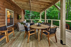 A wooden deck with a round table and chairs, surrounded by a wooden railing.