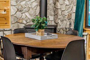 A round wooden dining table with a woven plant holder and a tray. - Rustic Ridge 3-Level Log Cabin, Covered Deck, Hot Tub, Adult Retreat, Kids Loft (Ellijay)