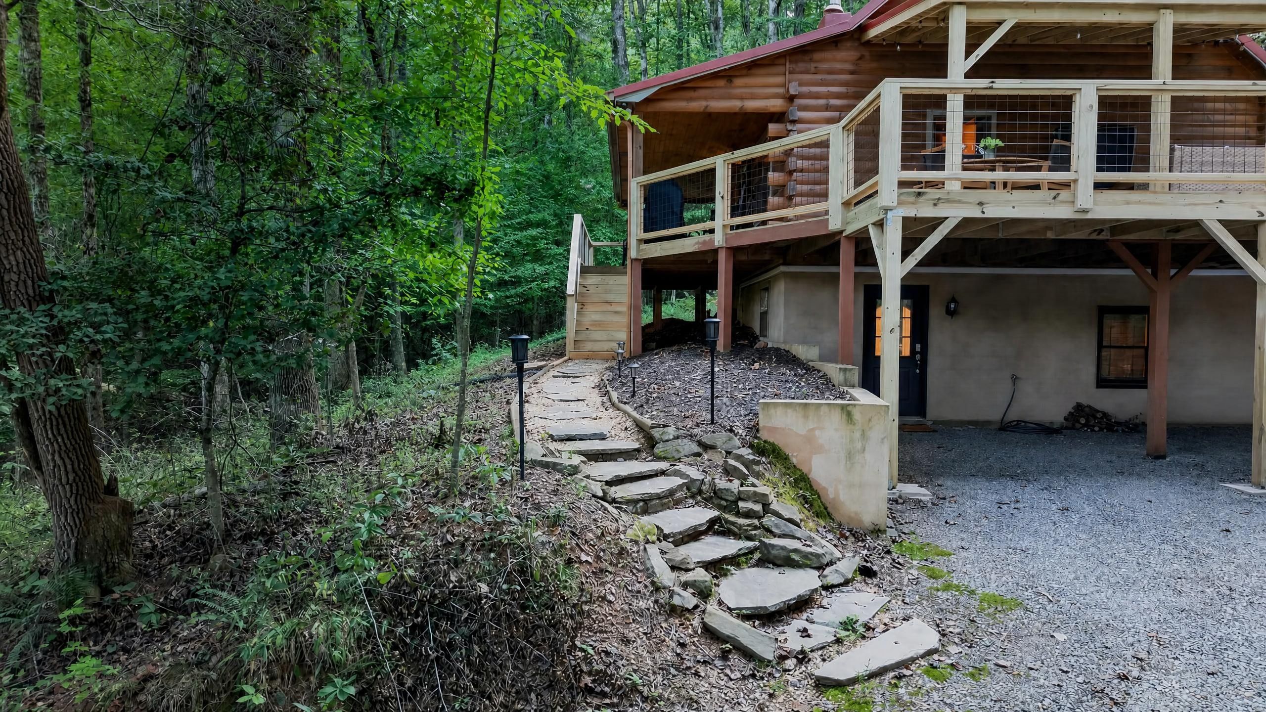 Eine Holzhütte mit einem Steinweg, der zu einer Holzdar Terrasse führt.