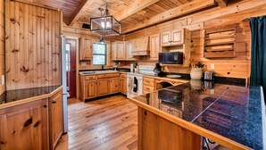 A wooden cabin-style kitchen with wooden cabinets, a granite countertop, a microwave, and a coffee maker. - Rustic Ridge- A cozy 2-bedroom+loft cabin outside Elijay w/hottub, firepit. (Ellijay)