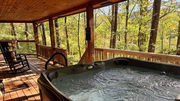 A hot tub on a wooden deck with a view of a forest. - Rustic Ridge- A cozy 2-bedroom+loft cabin outside Elijay w/hottub, firepit. (Ellijay)