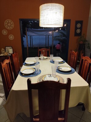 A dining area with a table set for four, chairs, a hanging light fixture, and decorative plates on the wall.