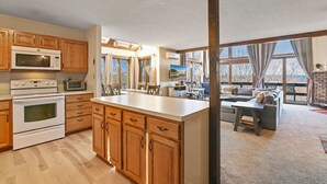A spacious kitchen with wooden cabinets, a large island, and a dining area with a sofa and table. - Pocono Mountains Camelback Retreat-Stunning Views (Tannersville)