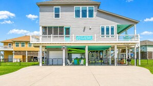 A two-story building with a balcony and a sign that reads 'Meraki Isle.' - Beach View 4BR | Sleeps 14 | Fenced Yard (Crystal Beach)