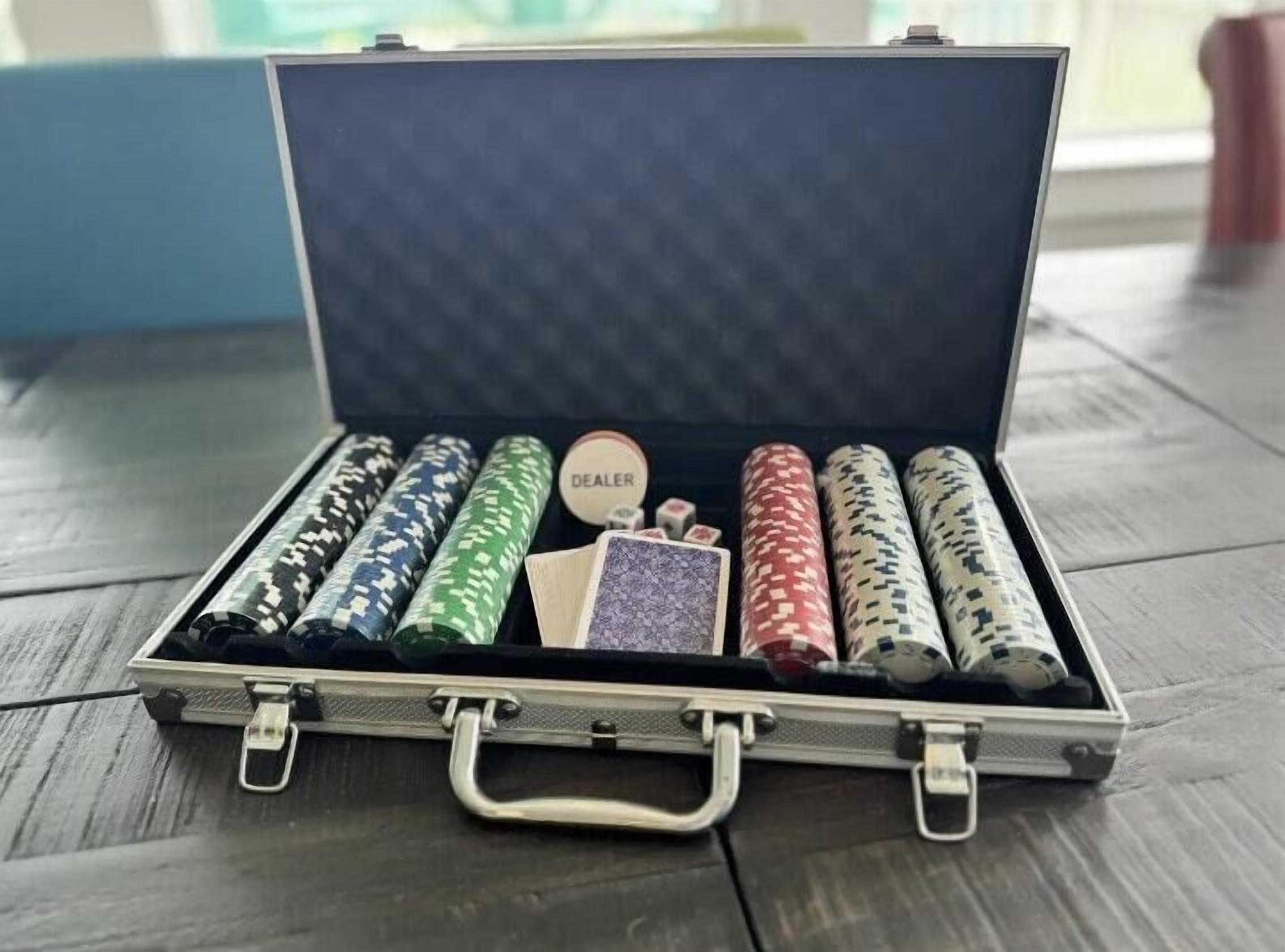 A briefcase with poker chips and a dealer button on a wooden surface.