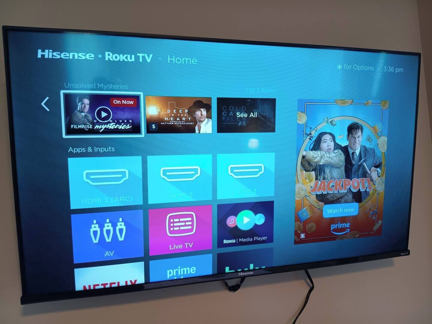 A Hisense TV displaying the Roku TV Home screen with various streaming apps and content options.