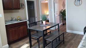A kitchen with wooden cabinets, a granite countertop, and a dining table with benches. - The Micro-Loft at Mt. Pleasant New 2BR APT Parking (Providence)