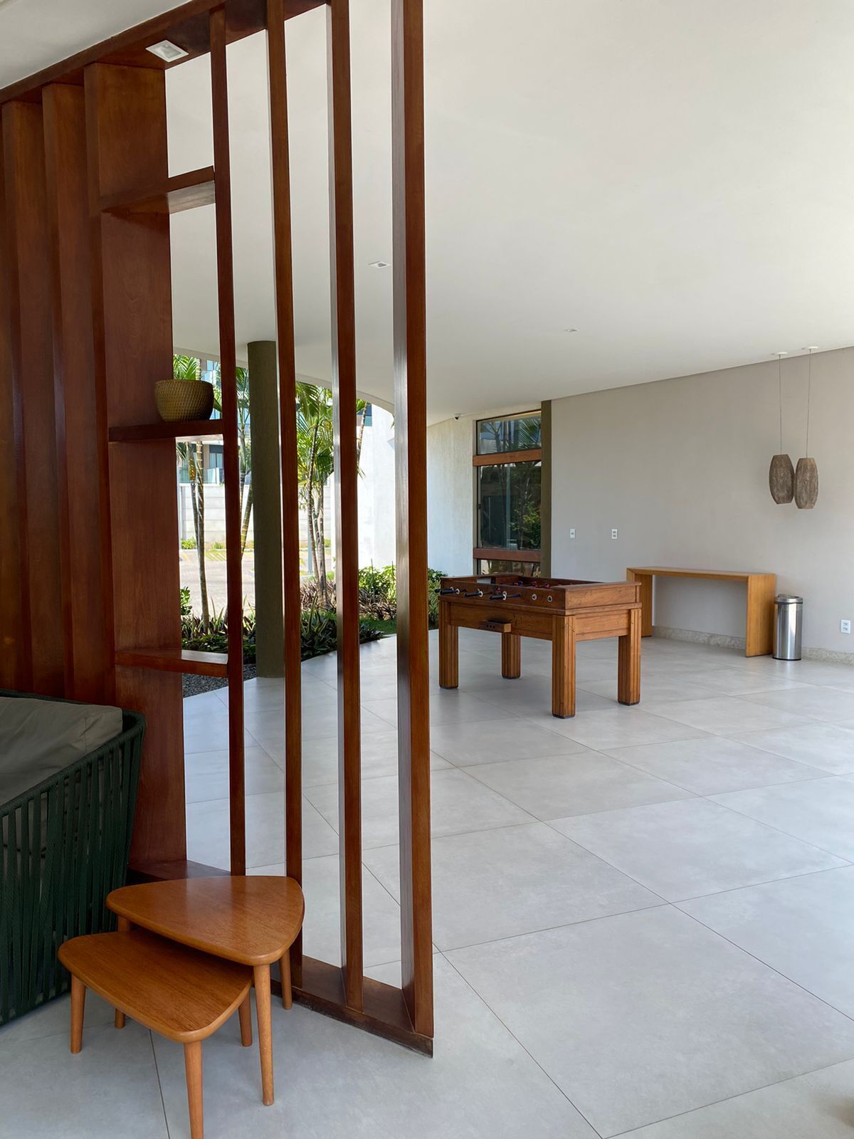 A spacious room with a wooden partition, a green sofa, a wooden table, and a foosball table.