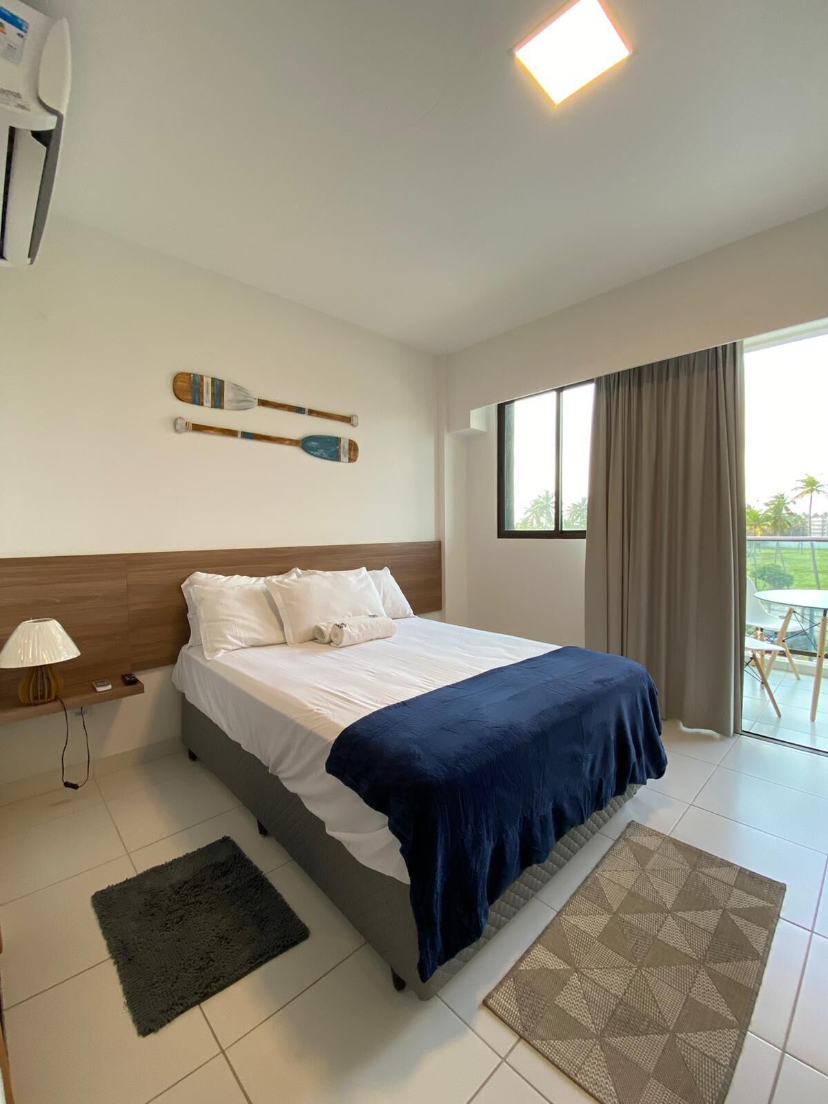 Habitación de hotel con cama, escritorio, silla, ventana con cortinas y vistas al exterior.