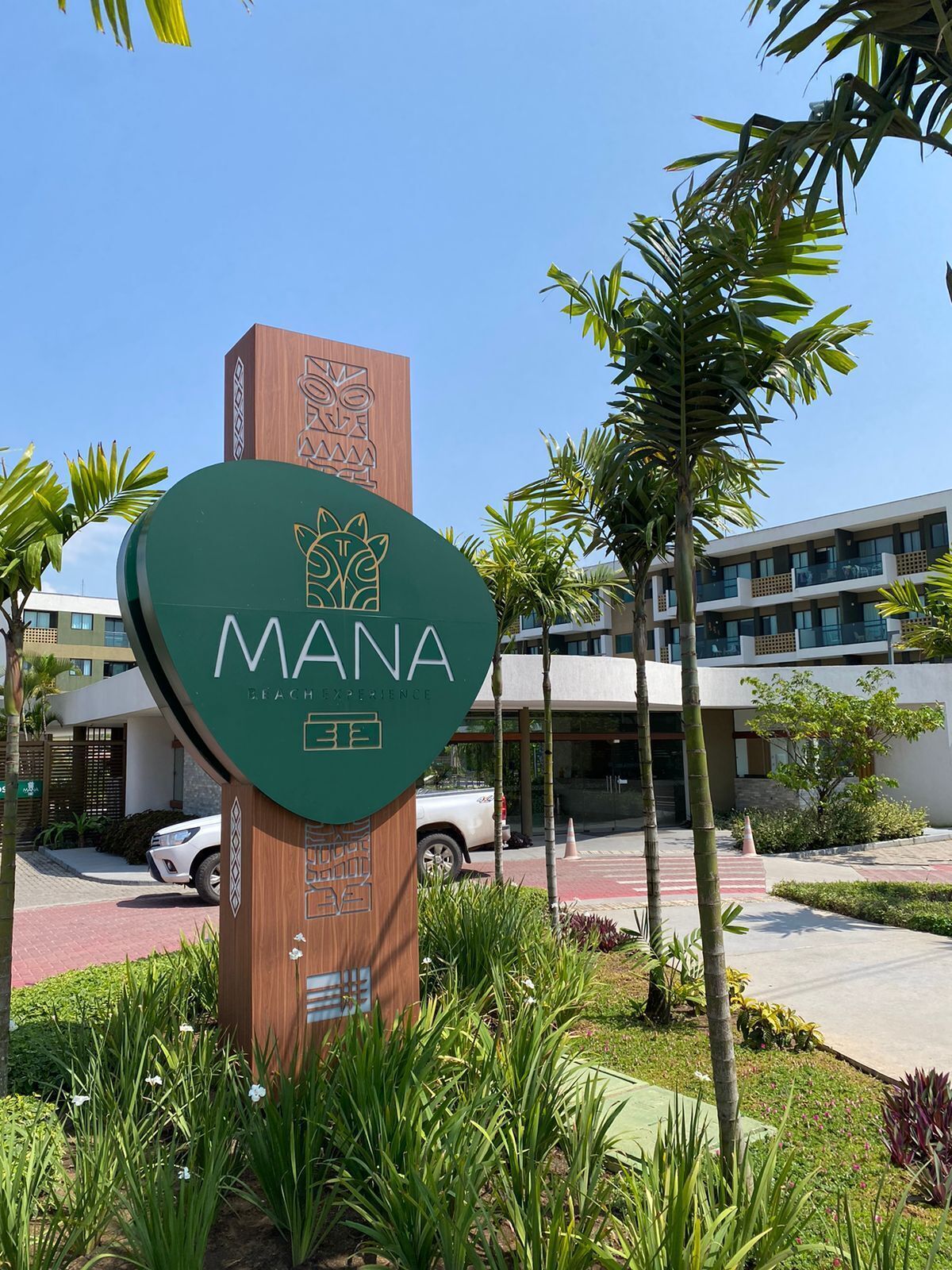 Un cartel que dice "MANA Beach Experience" con un edificio moderno al fondo.