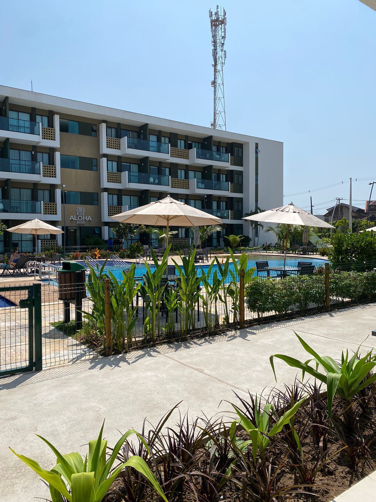 A hotel with a swimming pool, outdoor seating, and a modern building facade.
