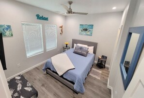 A bedroom with a bed, a ceiling fan, a window with blinds, and a wall-mounted artwork. - Madera Coastal l Waterfront 110 Feet (Rockport)