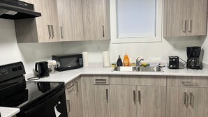 Una cocina moderna con armarios de madera, microondas, cafetera y pileta.