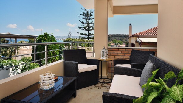 A balcony with wicker furniture, a small table, and a lantern.