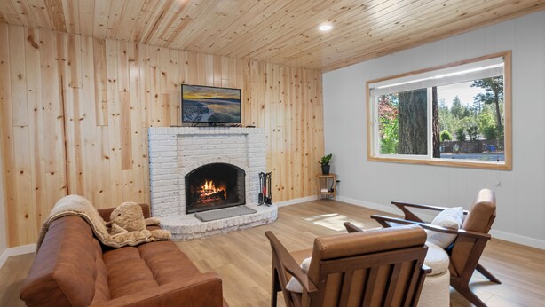 Un salon chaleureux avec une cheminée, des murs en bois, une grande fenêtre et des sièges confortables.