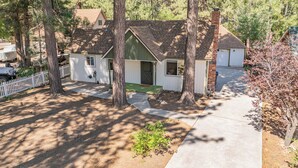 Une maison de plain-pied avec une porte d’entrée verte, une cheminée en briques et une clôture blanche en bois.