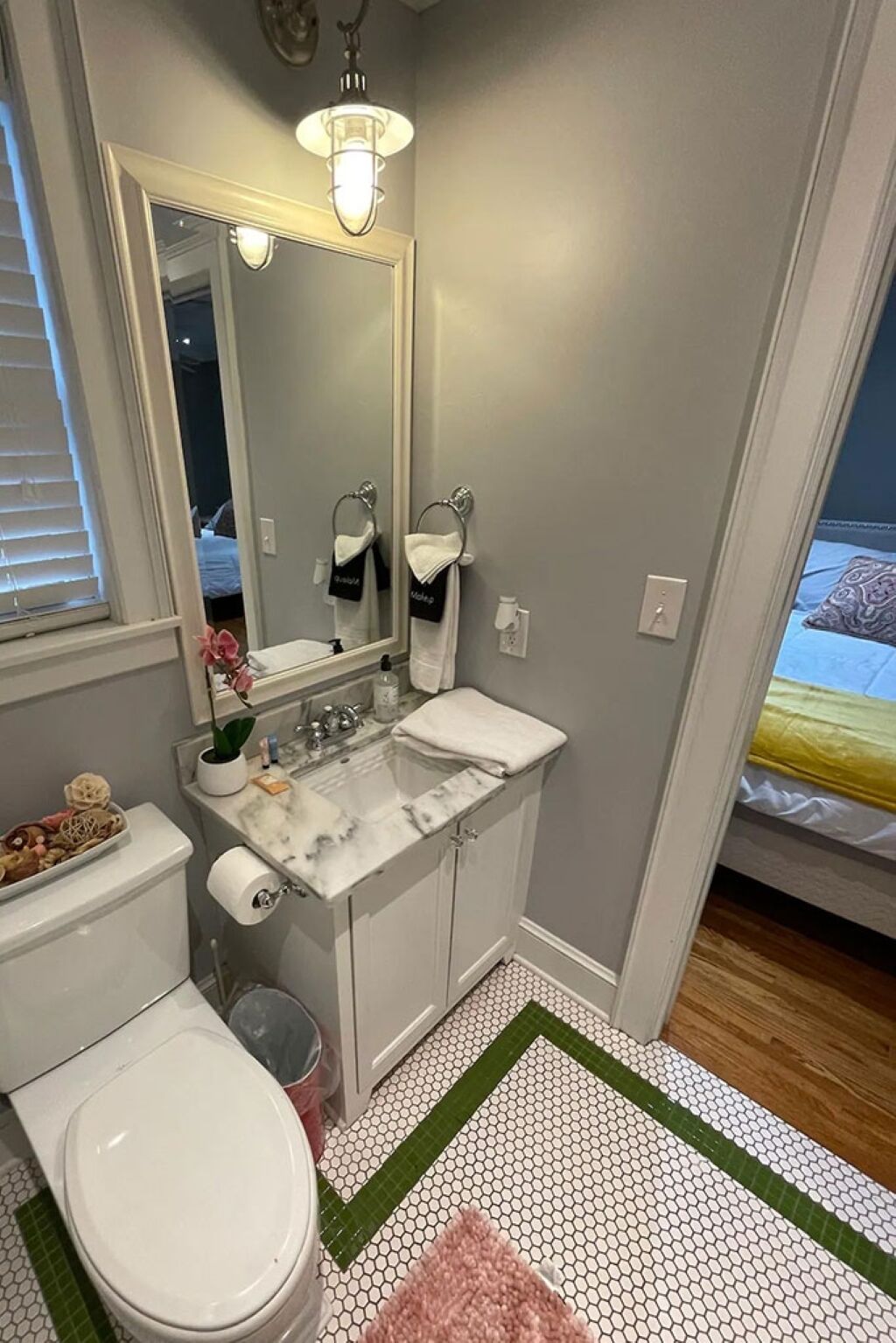 A bathroom with a toilet, sink, and mirror.