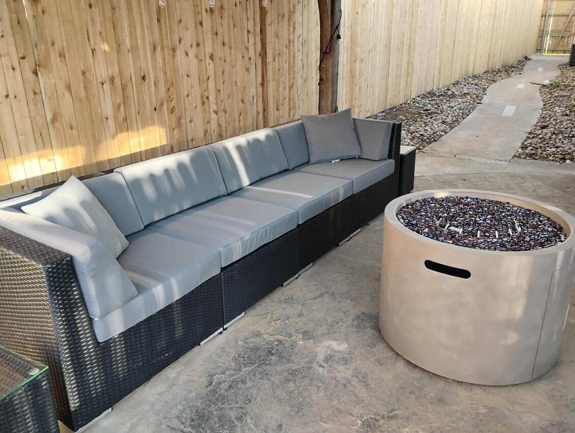 A modern outdoor seating area with a grey sofa and a round planter.