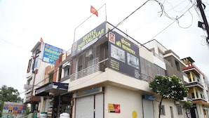 A hotel with a signboard advertising a luxury room, contact numbers, and a flag. - Hotel Shri Salasar (Ujjain)