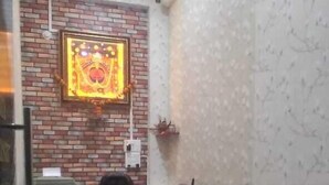 A compact living space with a sofa, a dining area with chairs, a kitchen counter, and a decorative wall piece. - Hotel Shri Salasar (Ujjain)