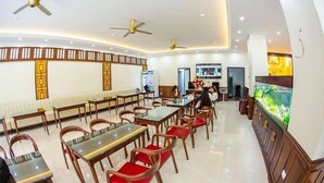 A restaurant with multiple tables and chairs, ceiling fans, and a fish tank. -  Ruby Ha Long 6 Hotel (Bai Chay)