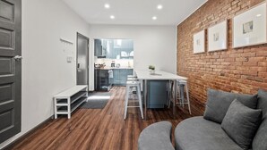 A modern kitchen with a dining area, a gray sofa, and a brick accent wall. - Cozy&Modern 2Bdr Apt PIttsburgh (Pittsburgh)